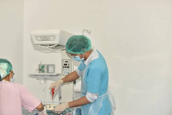 Team surgeon at work in operating room. Surgical light in the operating room. Preparation for the beginning of surgical operation with a cut. The surgeon is performing surgery on the patient.