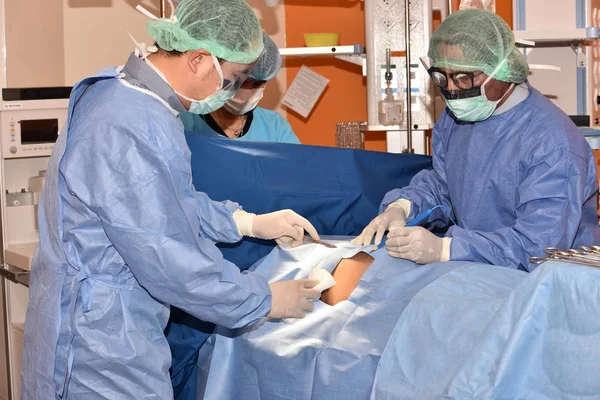 Team surgeon at work in operating room. Surgical light in the operating room. Preparation for the beginning of surgical operation with a cut. The surgeon is performing surgery on the patient.