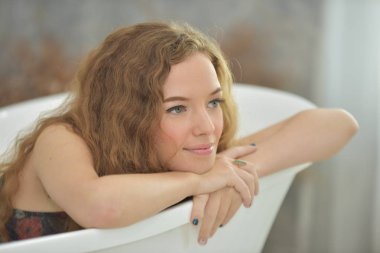 Tatlı bir gülümseme ile güzel bir kadın. Rahatlatıcı bir day.woman bathtub.relaxed zaman bathroom.young kadın küvette rahatlatıcı döşeme üzerinde güzel bir duruş.