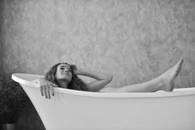 Bathtub.relaxed zamanında banyo döşeme genç bir kadın portresi. Güzel kadın. Güzel bir kızın beyaz pijamalı portre rahatlatıcı ile rahat bir tatil