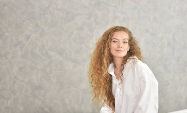 Güzel bir kızın beyaz pijamalı portre rahat bir tatil ile rahatlatıcı. Kadın sadece uyan el germe ile. Sabah streç. Sadece biraz daha zaman bed.young kadın bathtub.relaxed zamanında banyo döşeme. Güzel kadın.