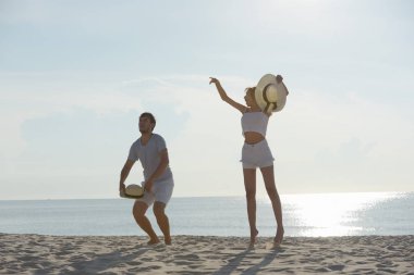 Genç çift egzersiz ve sabah erken sunrise plajda atlamak. Güzel sarı gökyüzü ile