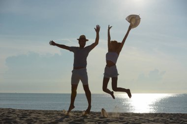 Genç çift egzersiz ve sabah erken sunrise plajda atlamak. Güzel sarı gökyüzü ile