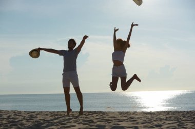 Genç çift egzersiz ve sabah erken sunrise plajda atlamak. Güzel sarı gökyüzü ile