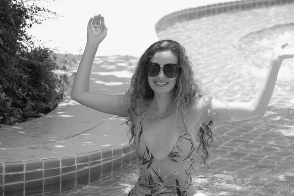 Güzel kız havuz başında güzel bir mayo parlak bir günde. Güzel zarif yanık tenli kadın bikini ve güneş gözlüğü yüzme havuzu Spa'da rahatlatıcı portresi. Sıcak yaz günü ve parlak güneşli ışık.