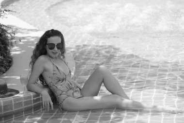 Güzel kız havuz başında güzel bir mayo parlak bir günde. Güzel zarif yanık tenli kadın bikini ve güneş gözlüğü yüzme havuzu Spa'da rahatlatıcı portresi. Sıcak yaz gün ve parlak güneşli