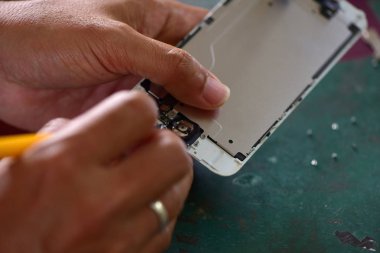 Yakın çekim, A insan el tamir Smartphone ile Screwdriver.Internal devreler ve cep telefonları yapısal unsurları. Cep telefonları ve tablet yetenekli teknisyenler tarafından onarılıyor. Deneyimli test ve onay cep telefonları. Önce ve sonra onarım