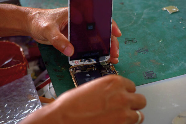Close-up Of A Human Hand Repairing Smartphone With Screwdriver.Internal circuits and structural elements of mobile phones.Repairing mobile phones and tablets by skilled technicians.Experienced testers and check mobile phones. Before and After Repair