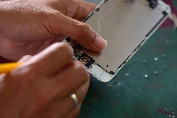 Close-up Of A Human Hand Repairing Smartphone With Screwdriver.Internal circuits and structural elements of mobile phones.Repairing mobile phones and tablets by skilled technicians.Experienced testers and check mobile phones. Before and After Repair