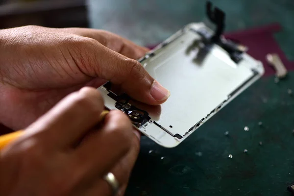 Close-up Of A Human Hand Repairing Smartphone With Screwdriver.Internal circuits and structural elements of mobile phones.Repairing mobile phones and tablets by skilled technicians.Experienced testers and check mobile phones. Before and After Repair