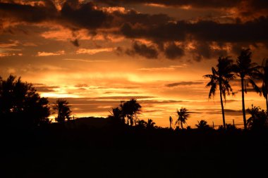 Dağın zirvesine günbatımı manzara. Turuncu-kırmızı bulutun turuncu gökyüzü ve üst üste gelen dağ manzaraları vardır.
