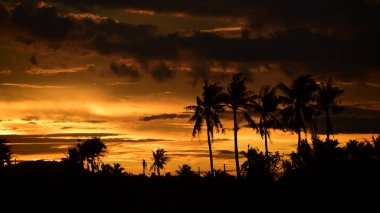 Dağın zirvesine günbatımı manzara. Turuncu-kırmızı bulutun turuncu gökyüzü ve üst üste gelen dağ manzaraları vardır.