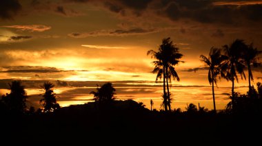 Dağın zirvesine günbatımı manzara. Turuncu-kırmızı bulutun turuncu gökyüzü ve üst üste gelen dağ manzaraları vardır.
