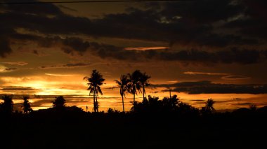 Dağın zirvesine günbatımı manzara. Turuncu-kırmızı bulutun turuncu gökyüzü ve üst üste gelen dağ manzaraları vardır.