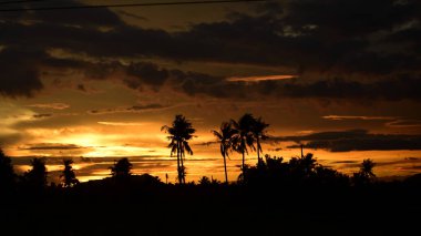 Dağın zirvesine günbatımı manzara. Turuncu-kırmızı bulutun turuncu gökyüzü ve üst üste gelen dağ manzaraları vardır.