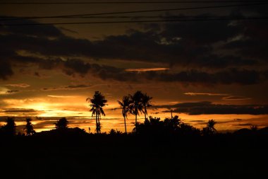 Dağın zirvesine günbatımı manzara. Turuncu-kırmızı bulutun turuncu gökyüzü ve üst üste gelen dağ manzaraları vardır.