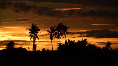 Dağın zirvesine günbatımı manzara. Turuncu-kırmızı bulutun turuncu gökyüzü ve üst üste gelen dağ manzaraları vardır.