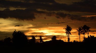 Dağın zirvesine günbatımı manzara. Turuncu-kırmızı bulutun turuncu gökyüzü ve üst üste gelen dağ manzaraları vardır.