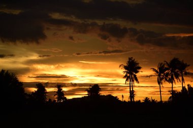 Dağın zirvesine günbatımı manzara. Turuncu-kırmızı bulutun turuncu gökyüzü ve üst üste gelen dağ manzaraları vardır.