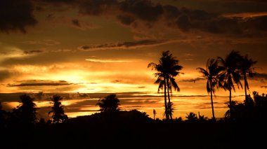 Dağın zirvesine günbatımı manzara. Turuncu-kırmızı bulutun turuncu gökyüzü ve üst üste gelen dağ manzaraları vardır.