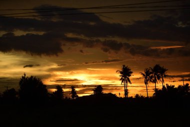 Dağın zirvesine günbatımı manzara. Turuncu-kırmızı bulutun turuncu gökyüzü ve üst üste gelen dağ manzaraları vardır.