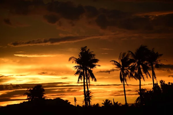 Dağın zirvesine günbatımı manzara. Turuncu-kırmızı bulutun turuncu gökyüzü ve üst üste gelen dağ manzaraları vardır.