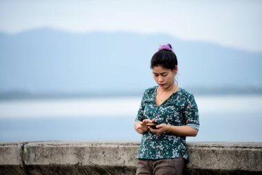 Asyalı kadın cep telefonu açık havada kullanarak