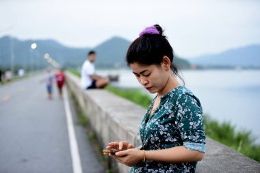 Asyalı kadın cep telefonu açık havada kullanarak