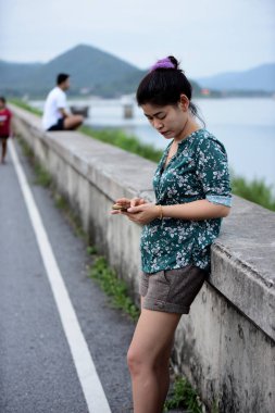 Asyalı kadın cep telefonu açık havada kullanarak