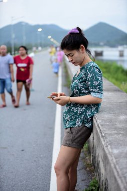 Asyalı kadın cep telefonu açık havada kullanarak