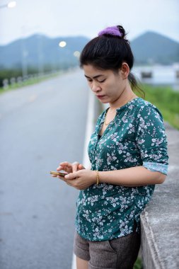 Asyalı kadın cep telefonu açık havada kullanarak