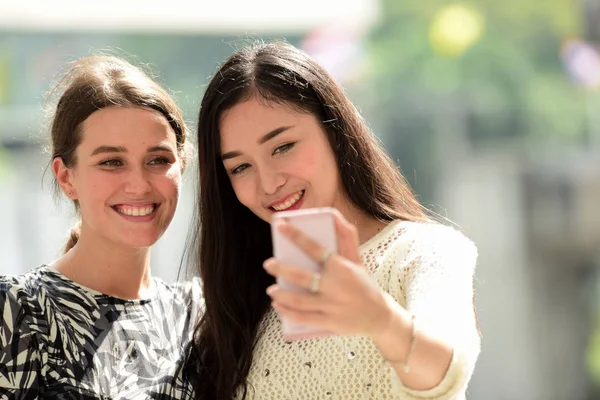 Two girl friends is doing selfie on mobile phone