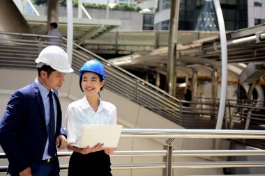 İki mimar inşaat alanında dizüstü bilgisayar kullanıyor.