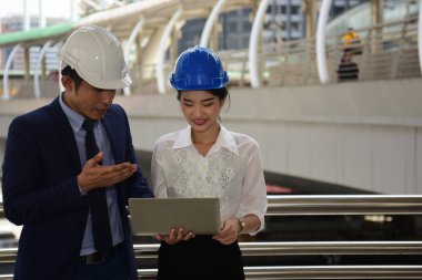 İki mimar inşaat alanında dizüstü bilgisayar kullanıyor.