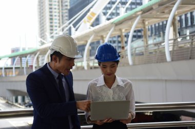 İki mimar inşaat alanında dizüstü bilgisayar kullanıyor.