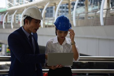 İki mimar inşaat alanında dizüstü bilgisayar kullanıyor.