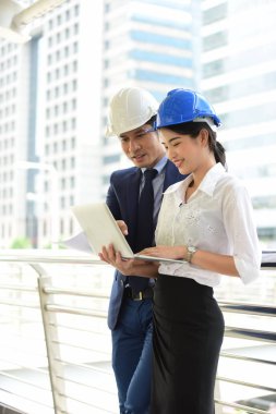 İki mimar inşaat alanında dizüstü bilgisayar kullanıyor.
