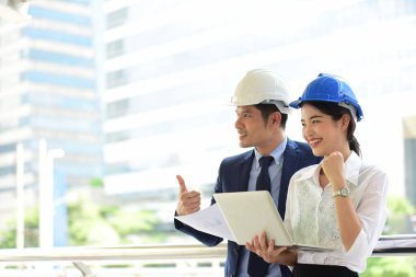 İki mimar inşaat alanında dizüstü bilgisayar kullanıyor.