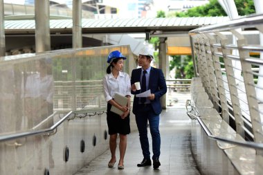 İki mimar inşaat alanında konuşuyor.