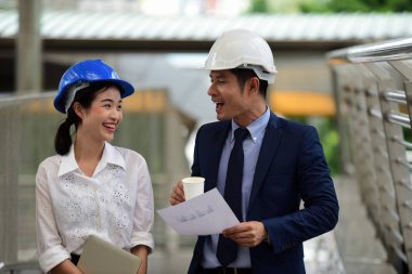 İki mimar inşaat alanında konuşuyor.