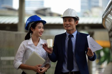 İki mimar inşaat alanında konuşuyor.