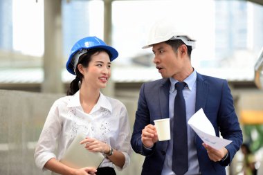 İki mimar inşaat alanında konuşuyor.