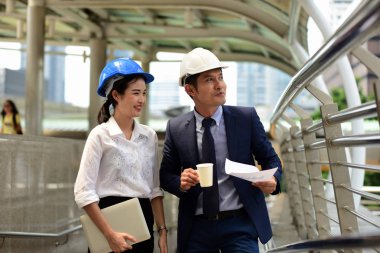 İki mimar inşaat alanında konuşuyor.