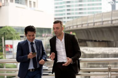 Açık havada konuşurken iki iş adamları. İki genç iş adamları iş bölgesinin ortasında durmak.