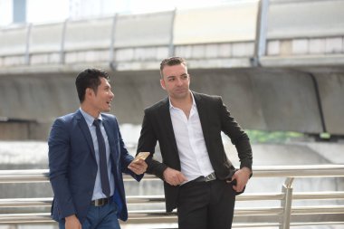 Açık havada konuşurken iki iş adamları. İki genç iş adamları iş bölgesinin ortasında durmak.