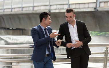Açık havada konuşurken iki iş adamları. İki genç iş adamları iş bölgesinin ortasında durmak.