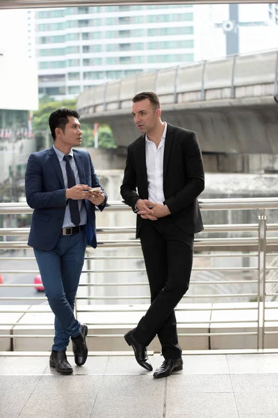 Açık havada konuşurken iki iş adamları. İki genç iş adamları iş bölgesinin ortasında durmak.