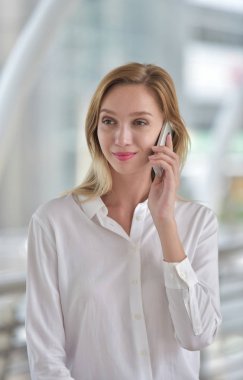 Kafkasyalı sarışın kadın cep telefonuyla konuşuyor.