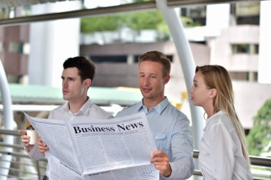 Üç iş adamı gazete okuyor ve şehir merkezinde tartışıyorlar.