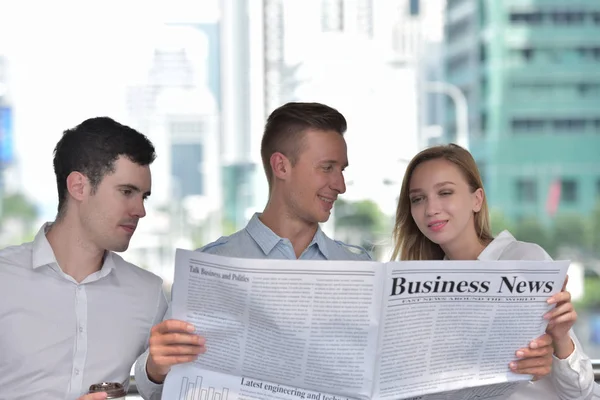 Three Business People Reading Newspaper Discussing City Center — Stock Photo, Image